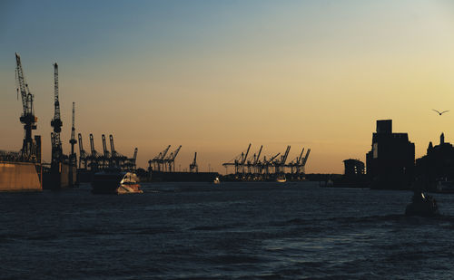 Commercial dock by sea against sky during sunset