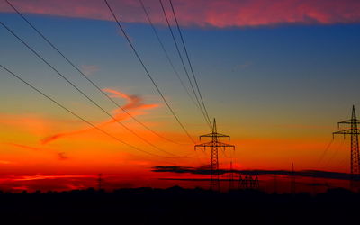 Silhouette electricity pylon against romantic sky at sunset