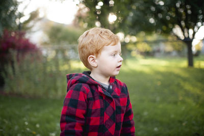 Boy looking away while standing against plants