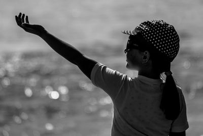 Rear view of girl with arm raised standing outdoors