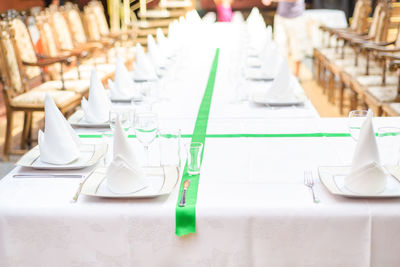 Long served table with plates, glasses, napkins and chairs