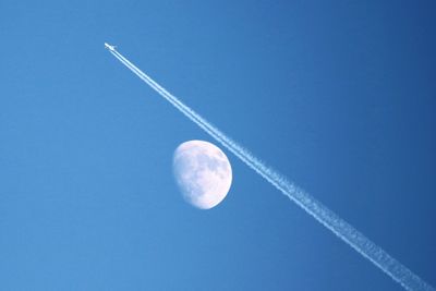 Low angle view of half moon against clear blue sky