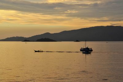 Boat sailing on sea against sky during sunset