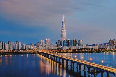 Illuminated modern buildings in city against sky at night