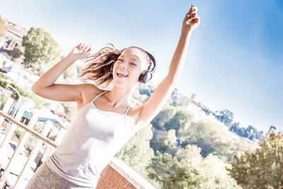 Portrait of smiling young woman standing against sky