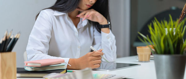 Midsection of woman using digital tablet in office