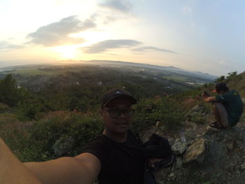 Portrait of young man on mountain against sky during sunset