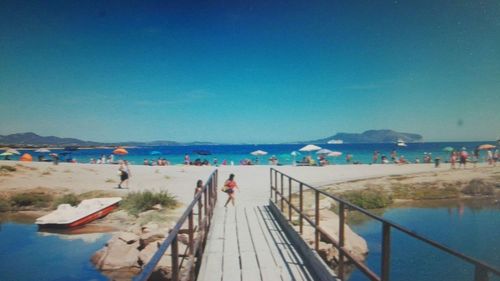 People on beach against clear blue sky