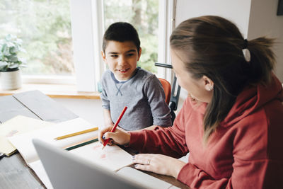 Mother teaching drawing to autistic son while sitting at home