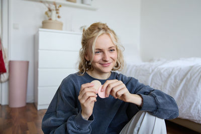 Portrait of young woman sitting on bed at home