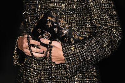 Midsection of woman standing against black background