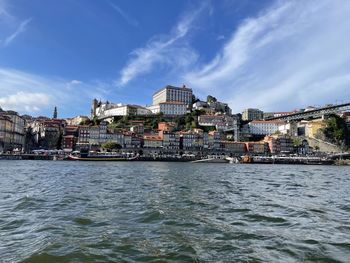 Buildings by river against sky
