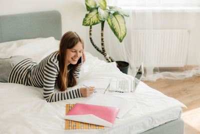 Portrait of young woman sitting on bed at home