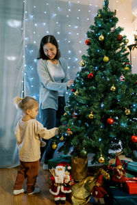 Portrait of girl playing christmas tree at home