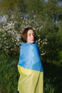 Portrait of young woman standing against plants