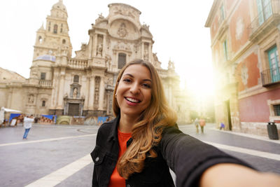 Portrait of young woman standing in city