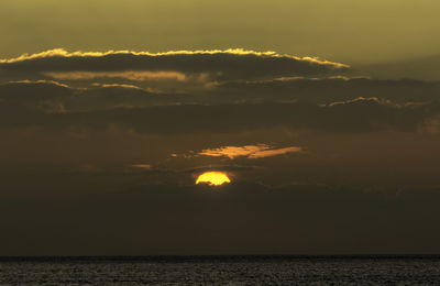 Scenic view of sea against dramatic sky during sunset