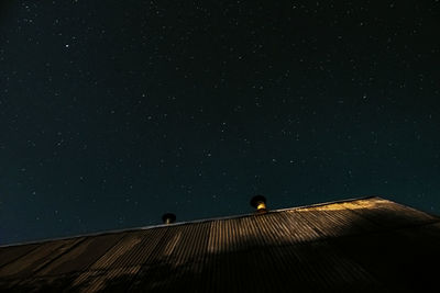 Photo of a roof illuminated by moonlight and the starry sky above it. stars, roof, dream. 