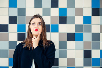 Portrait of beautiful young woman standing against wall