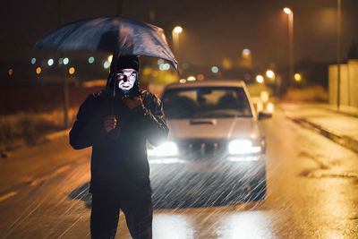 Man standing on illuminated street at night