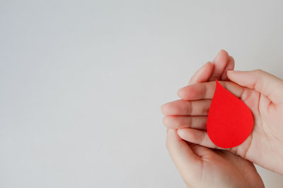 Cropped hand holding heart shape against white background