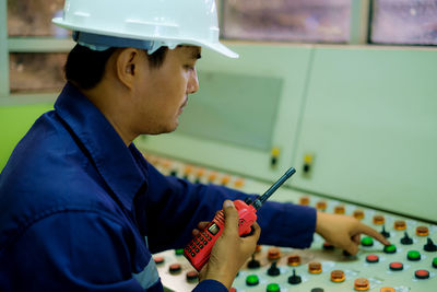 Engineer holding walkie-talkie while working in control room