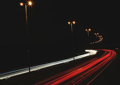 Light trails on road against sky at night