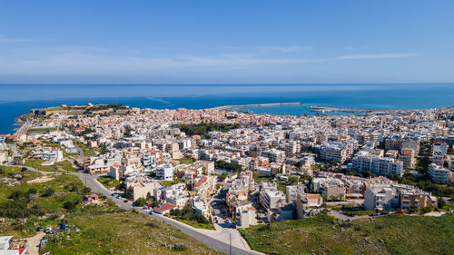 High angle view of townscape by sea against blue sky