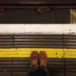 Low section of man standing on yellow line
