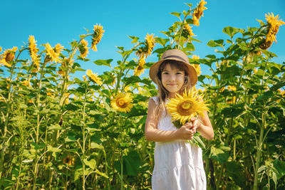 Portrait of girl wearing cap standing amidst plants