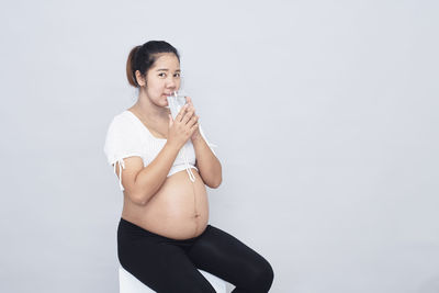 Young woman holding ice cream against white background