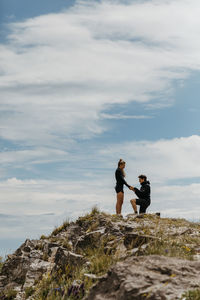 Friends standing on rock against sky