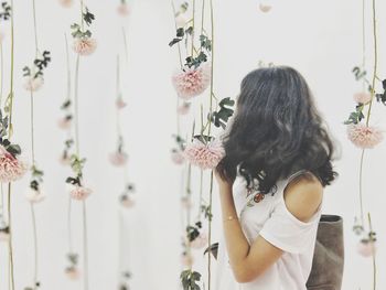 Rear view of woman standing by flowering plants