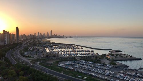 High angle view of city by sea against sky during sunset