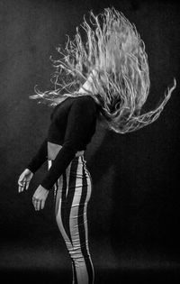 Woman with tousled hair against black background