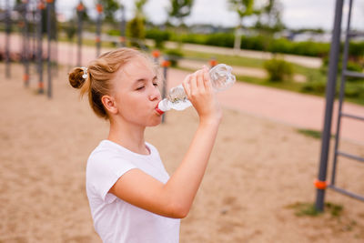 Full length of woman drinking water from land