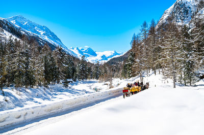 Val roseg, in engadine, switzerland, in winter, with carriages carrying tourists.