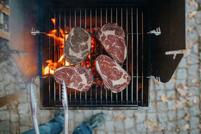 Close-up of hand grilling meat on barbecue grill