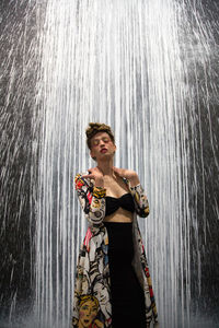 Beautiful woman wearing dress while standing against waterfall