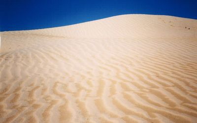 Scenic view of desert against blue sky