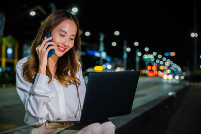 Portrait of young woman using digital tablet at night