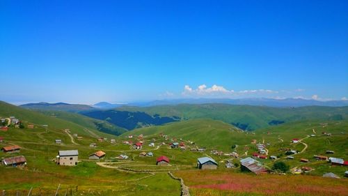 Scenic view of houses on grassy mountain against sky