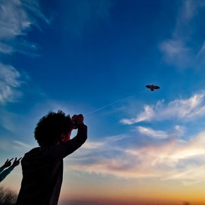 Low angle view of boy flying against blue sky