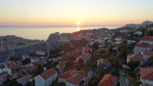 High angle view of townscape by sea against sky during sunset