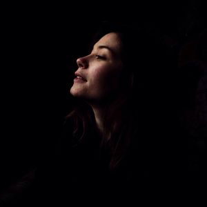 Portrait of young woman against black background