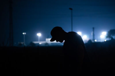 Silhouette man standing against illuminated sky at night