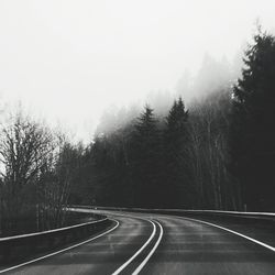 Empty road amidst trees against sky