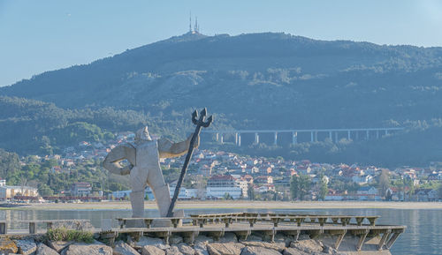Statue in city against mountain