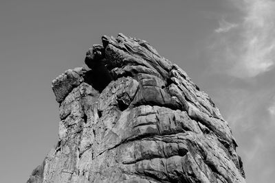 Low angle view of sculpture on rock against sky