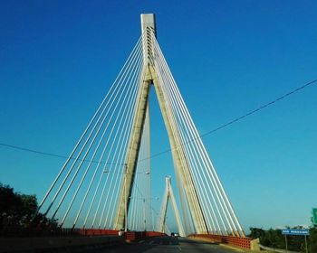 Low angle view of suspension bridge against blue sky